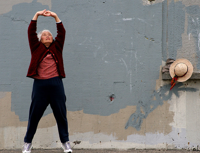 older woman pauses on street to stretch
